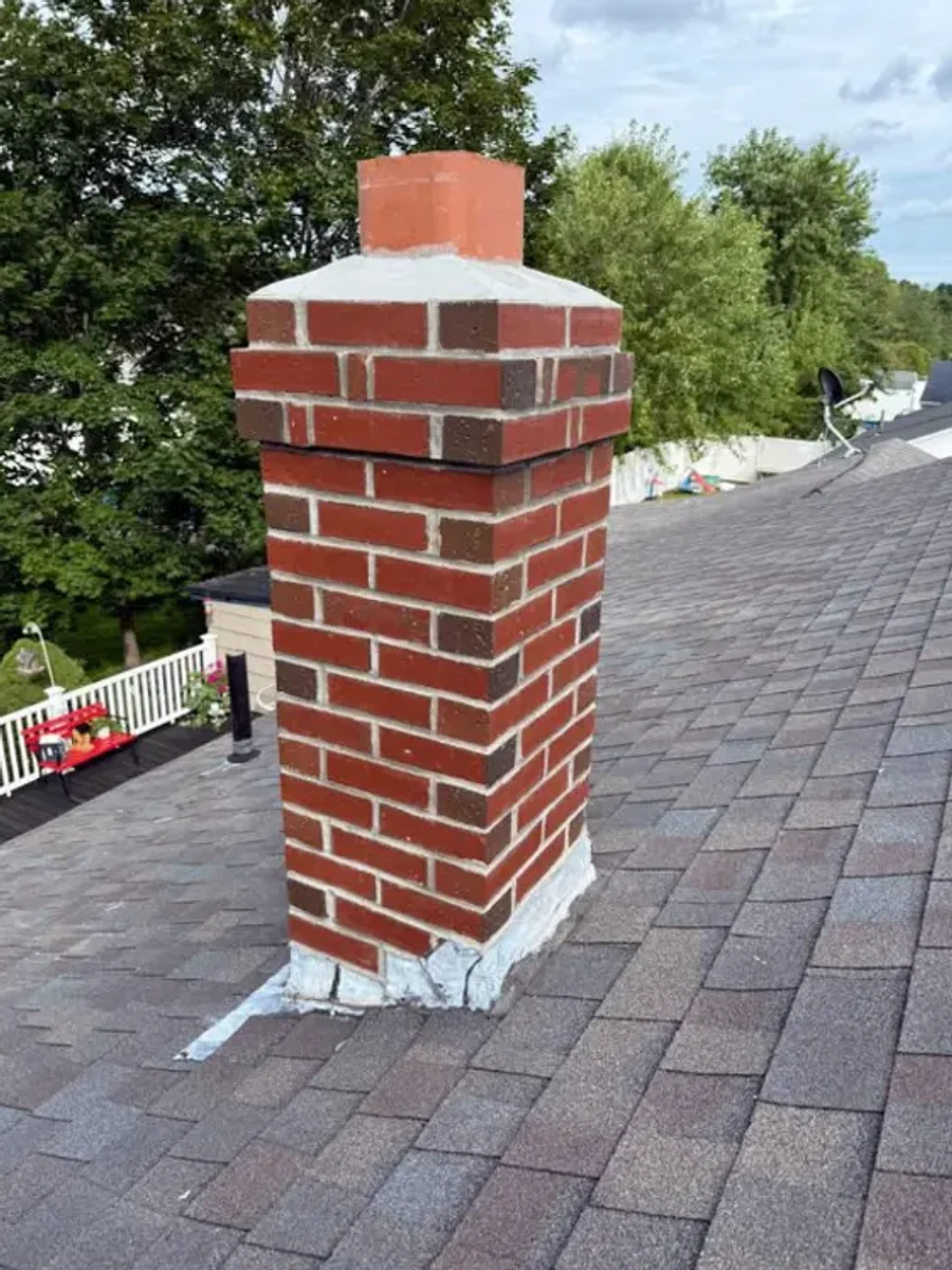 The same chimney rebuilt by All Chicago Construction with new brickwork, a fresh crown and a cap